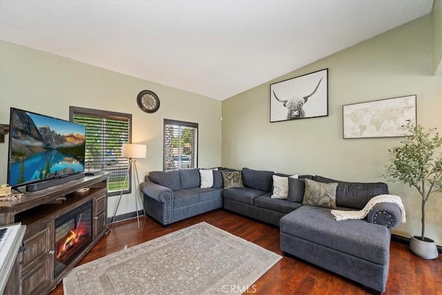 living area with a glass covered fireplace, vaulted ceiling, and wood finished floors