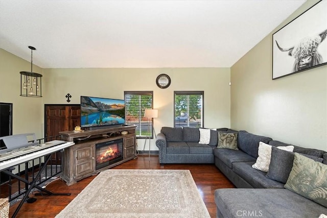 living area featuring a glass covered fireplace, dark wood-style flooring, and vaulted ceiling