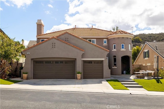 mediterranean / spanish house featuring an attached garage, a tiled roof, concrete driveway, and stucco siding