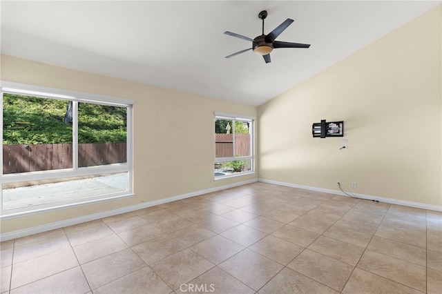 spare room with vaulted ceiling, light tile patterned floors, a ceiling fan, and baseboards