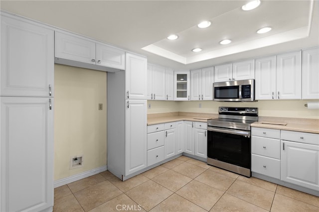 kitchen featuring a tray ceiling, stainless steel appliances, light countertops, and recessed lighting