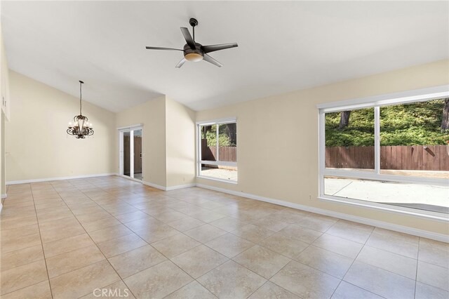 empty room with vaulted ceiling, light tile patterned floors, ceiling fan with notable chandelier, and baseboards