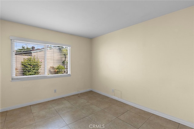 spare room featuring baseboards and light tile patterned floors