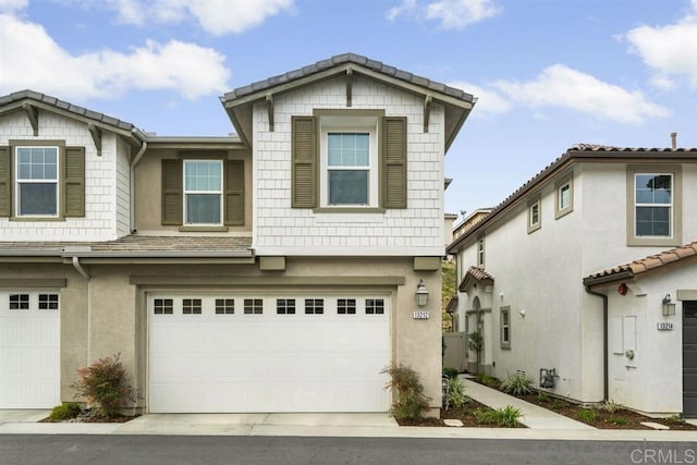 view of property with a garage, driveway, and stucco siding