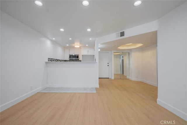 unfurnished living room featuring light wood-style flooring, visible vents, baseboards, and recessed lighting