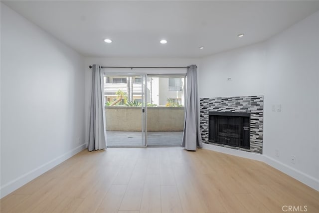 unfurnished living room featuring a fireplace, baseboards, and wood finished floors