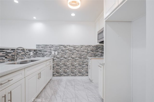 bathroom featuring marble finish floor, a sink, tile walls, and recessed lighting