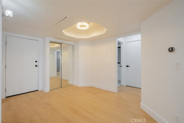 spare room with light wood finished floors, baseboards, and a tray ceiling