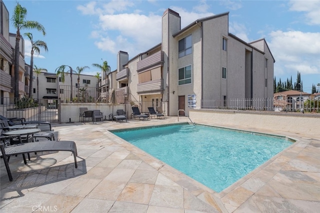 community pool featuring a residential view, a patio, and fence