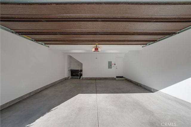 garage featuring baseboards, electric panel, and a garage door opener