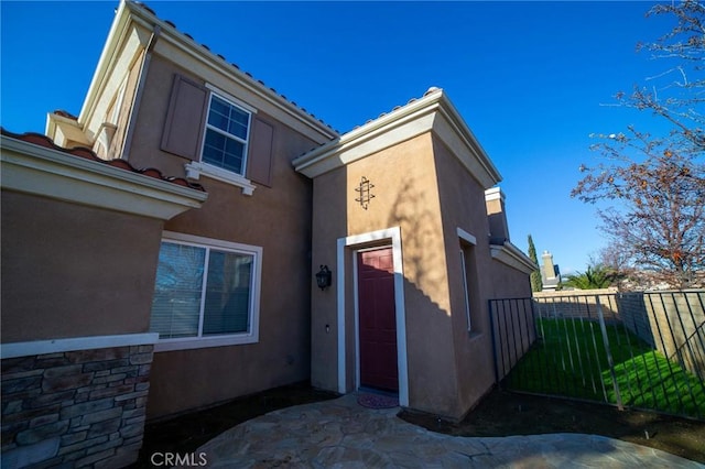 view of side of home featuring fence and stucco siding