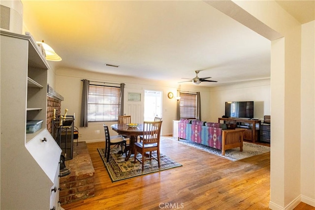 dining area with visible vents, wood finished floors, a ceiling fan, and baseboards