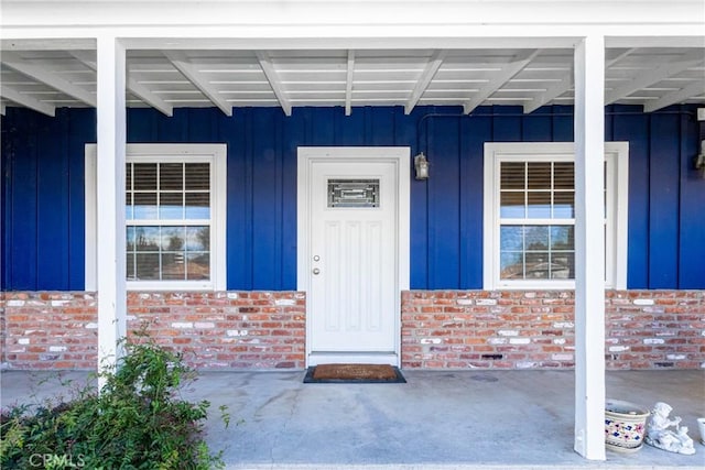 property entrance featuring board and batten siding and brick siding