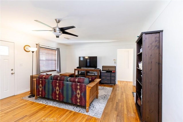 living room with ceiling fan, baseboards, and light wood-style floors