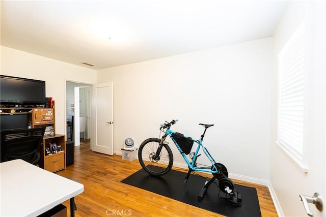 exercise room featuring light wood-style floors, visible vents, and baseboards