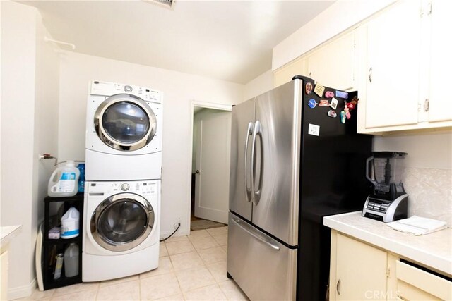 laundry room featuring stacked washer / drying machine, laundry area, and light tile patterned flooring