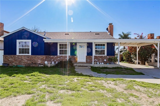 ranch-style home featuring brick siding, a chimney, board and batten siding, driveway, and a front lawn