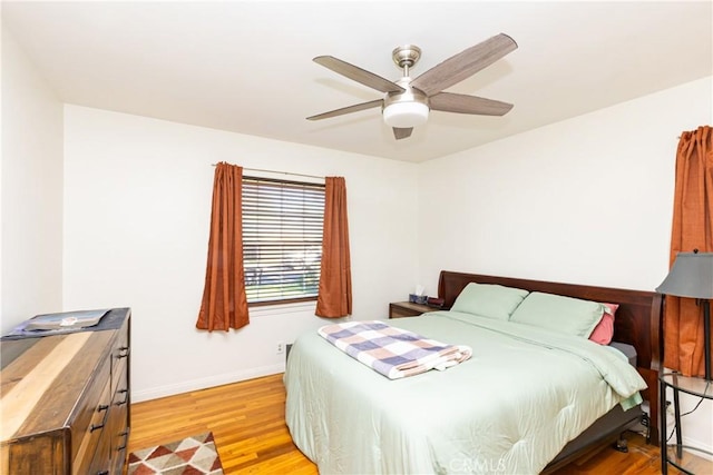 bedroom with ceiling fan, light wood-style flooring, and baseboards