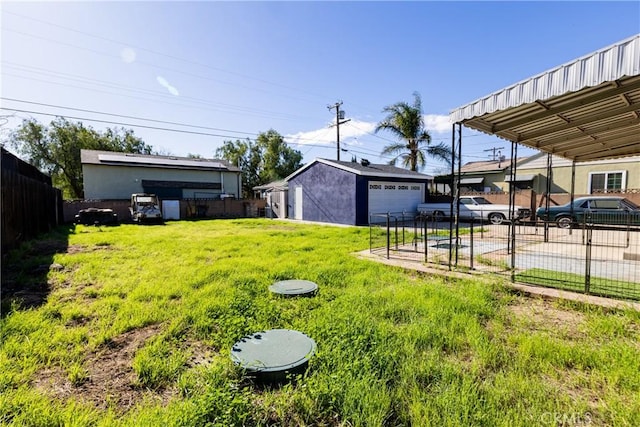 view of yard with a garage, fence, driveway, and an outdoor structure