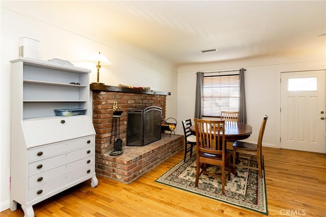 dining room with visible vents, a fireplace, and light wood-style flooring