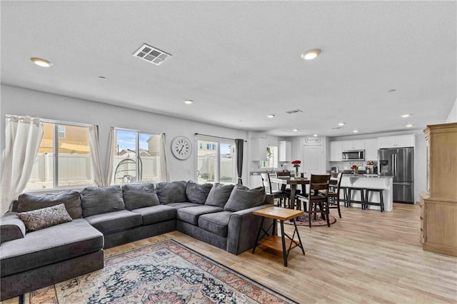 living area with light wood-type flooring, visible vents, and recessed lighting