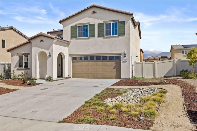 mediterranean / spanish-style home with a garage, a tile roof, fence, concrete driveway, and stucco siding