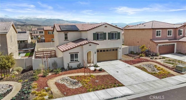 mediterranean / spanish house featuring a garage, roof mounted solar panels, fence, and concrete driveway