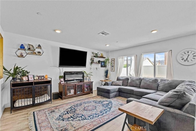 living area with light wood-type flooring, visible vents, and recessed lighting