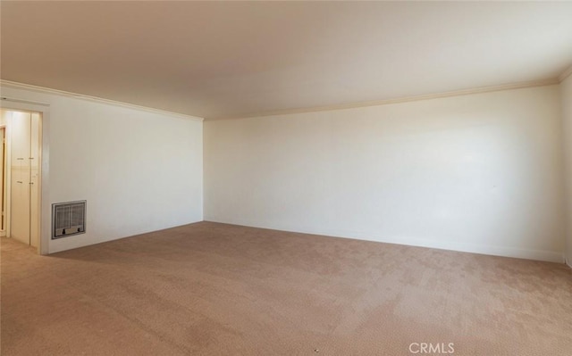 spare room with heating unit, crown molding, and carpet flooring