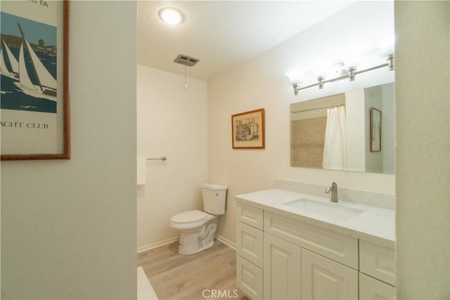 bathroom featuring toilet, wood finished floors, vanity, visible vents, and baseboards