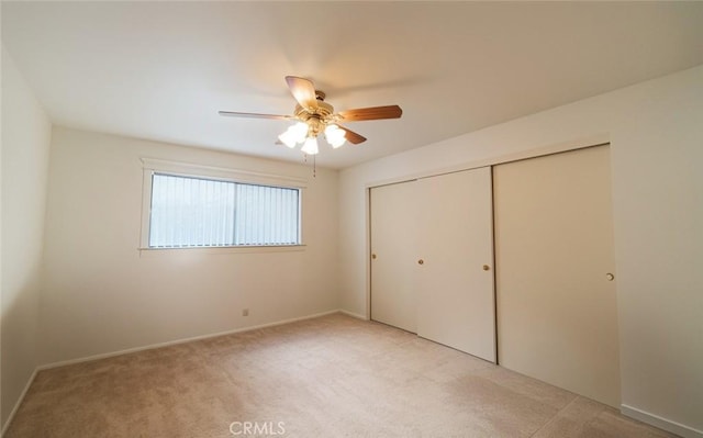 unfurnished bedroom featuring light carpet, a ceiling fan, and a closet