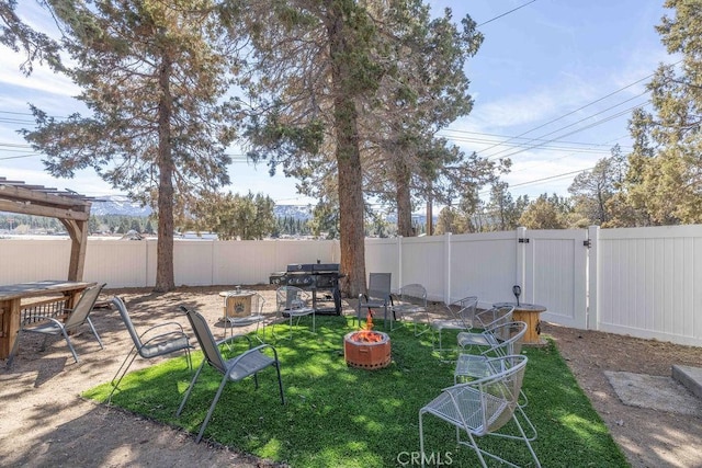 view of yard featuring an outdoor fire pit, a gate, and a fenced backyard