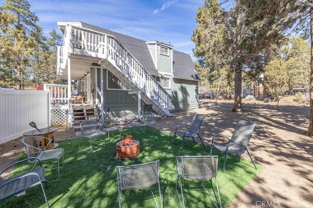 back of house with an outdoor fire pit, fence, a yard, roof with shingles, and stairway