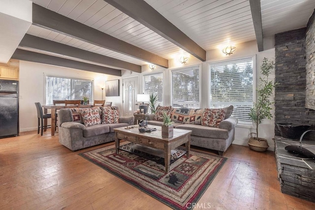 living room featuring beamed ceiling, baseboards, and hardwood / wood-style flooring