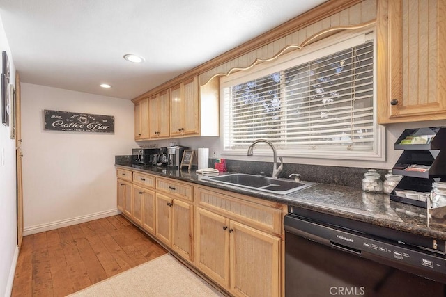 kitchen with dishwasher, light brown cabinetry, dark countertops, and a sink