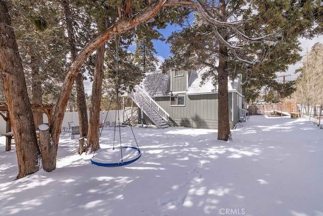 yard covered in snow featuring stairs and fence