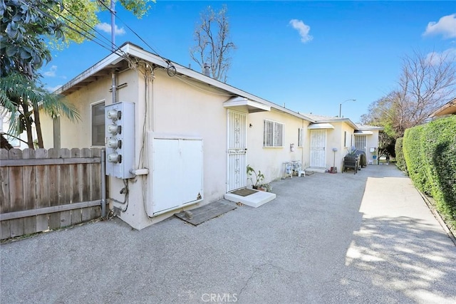 view of property exterior with a patio, fence, and stucco siding