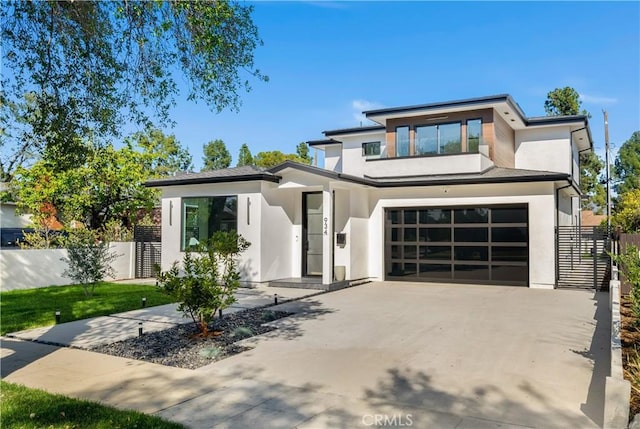 view of front facade featuring driveway, an attached garage, fence, and stucco siding