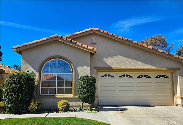 mediterranean / spanish home with a tiled roof, stucco siding, driveway, and an attached garage