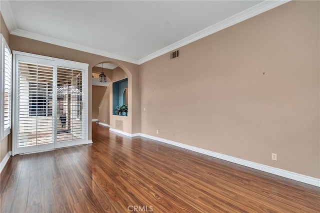 empty room featuring visible vents, baseboards, wood finished floors, and crown molding