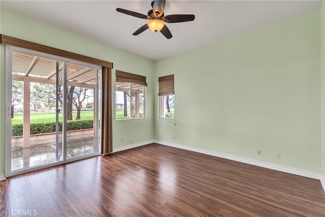 empty room with ceiling fan, baseboards, and dark wood-style floors