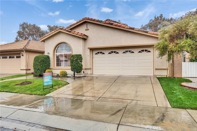 mediterranean / spanish home featuring a tile roof, a garage, driveway, and stucco siding