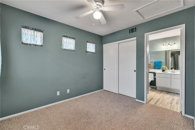 unfurnished bedroom featuring visible vents, baseboards, attic access, a closet, and light colored carpet