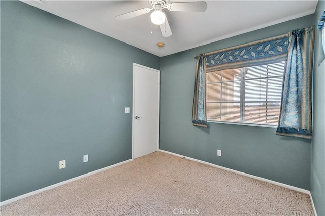 carpeted empty room with baseboards and a ceiling fan