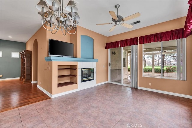 unfurnished living room with visible vents, arched walkways, baseboards, and ceiling fan with notable chandelier