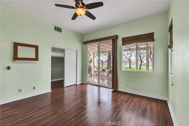 empty room featuring visible vents, baseboards, a ceiling fan, and wood finished floors