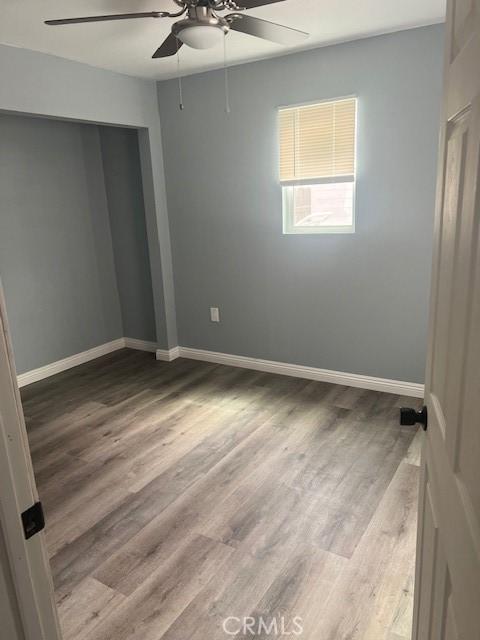 unfurnished bedroom featuring ceiling fan, wood finished floors, and baseboards