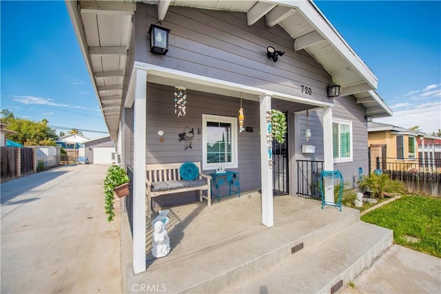 view of exterior entry featuring covered porch and fence