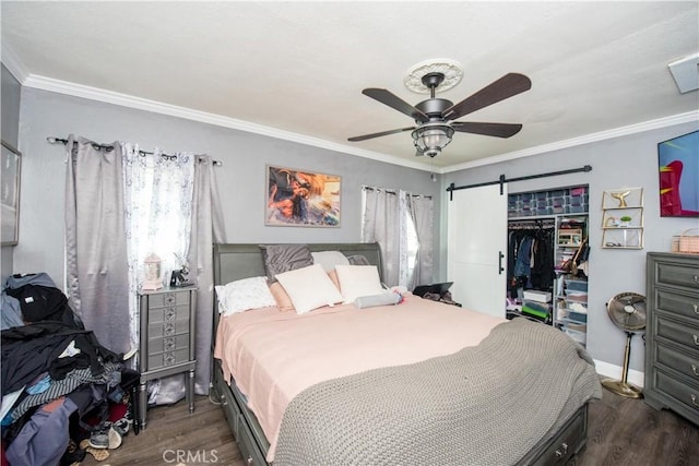 bedroom with ornamental molding, a barn door, a closet, and wood finished floors