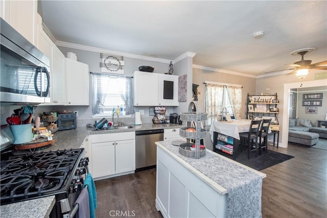 kitchen featuring appliances with stainless steel finishes, a sink, white cabinets, and crown molding